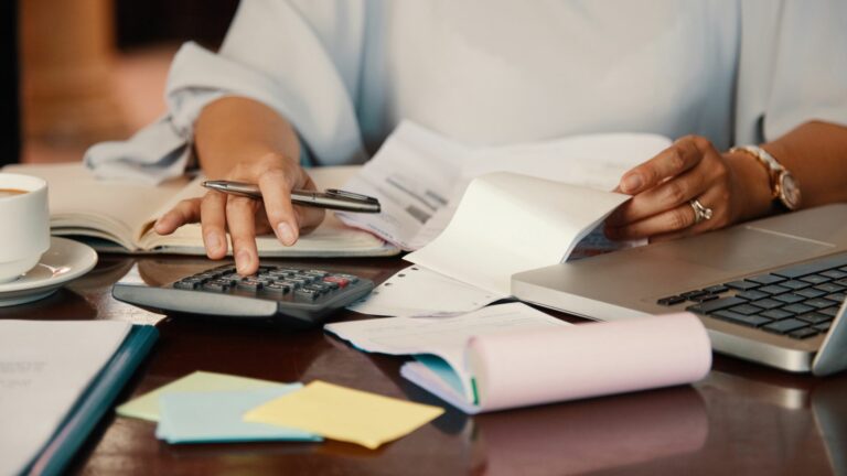 Professionnel de l’immobilier effectuant des calculs sur des documents financiers, illustrant les erreurs comptables en gestion immobilière et leur prévention